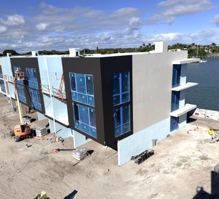 Aerial view of waterfront townhomes under construction with modern exterior finishes