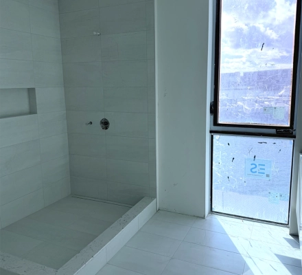 Tiled shower under construction with window providing natural light
